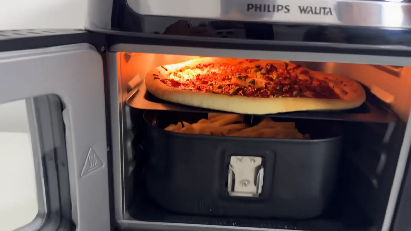 Cavidade iluminada com pizza assando e batatas na cesta inferior