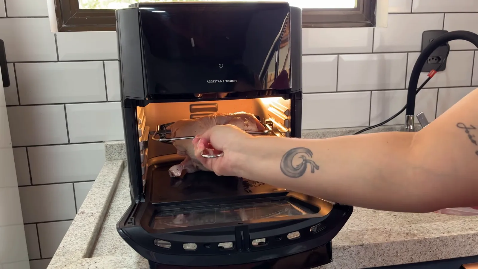 Frango inteiro sendo preparado com espeto rotisserie no forno elétrico