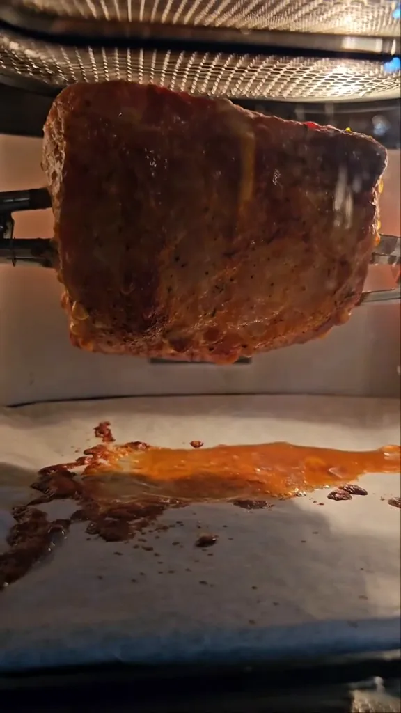 Carne assando e dourando no espeto rotisserie dentro da cavidade