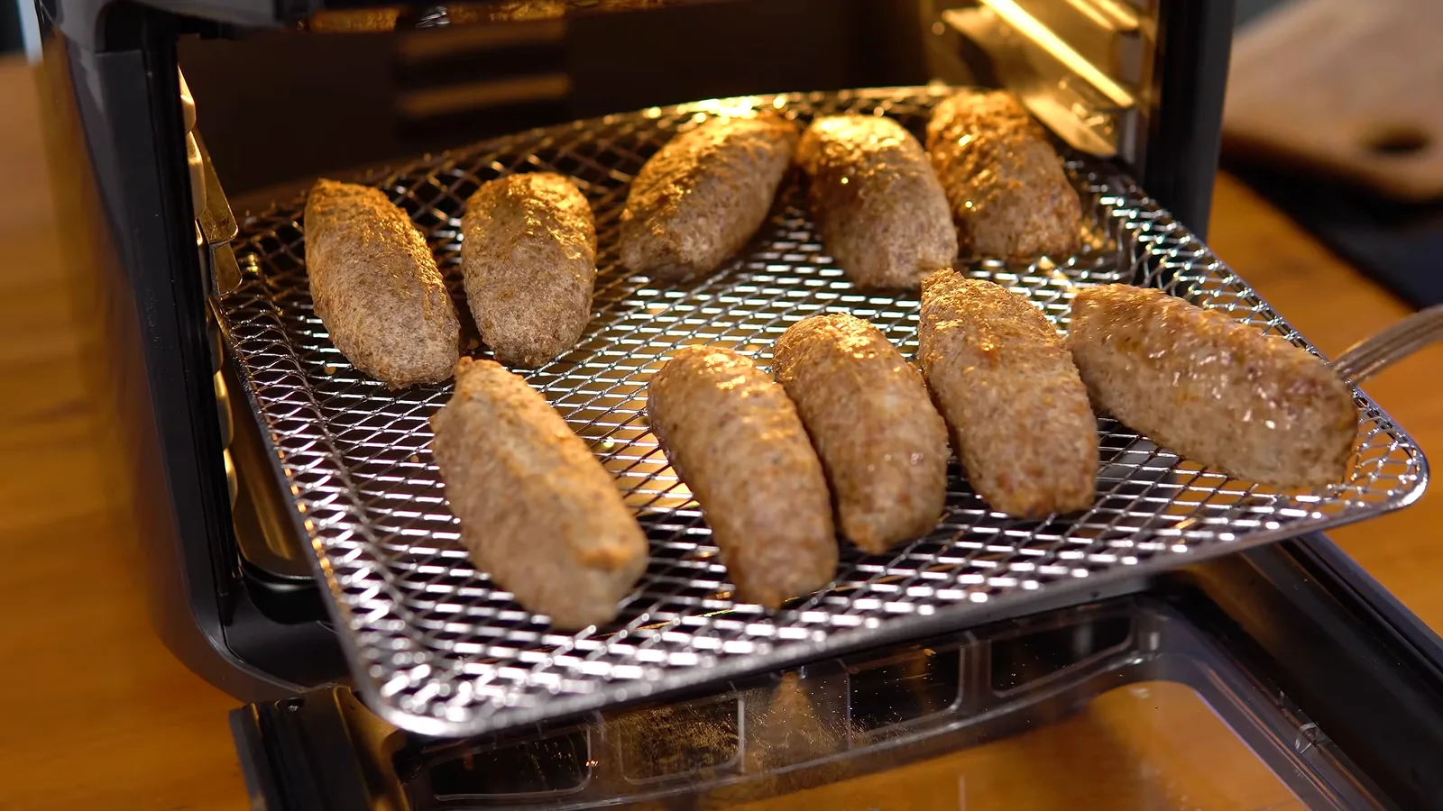 Alimentos sendo virados na grelha da air fryer Electrolux aberta