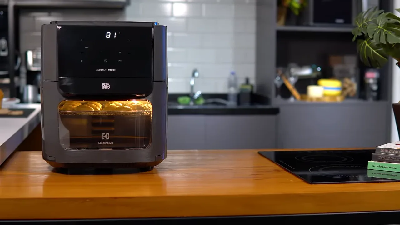 Air fryer assando pães de queijo com luz interna e painel ligados