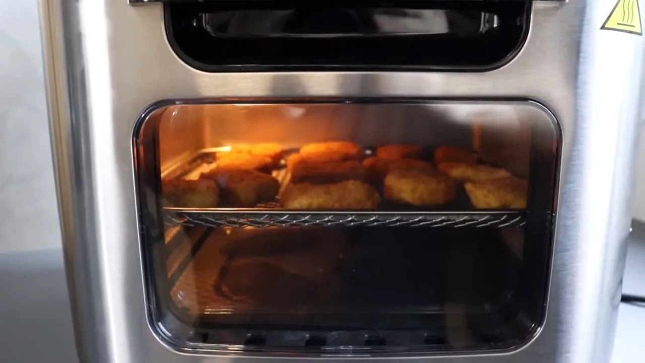 Alimentos assando no interior da fritadeira com iluminação interna acionada