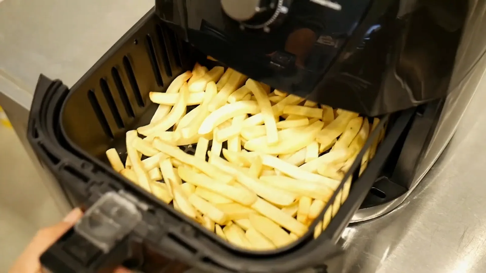 Cesto com batatas palito sendo colocado na fritadeira sem óleo