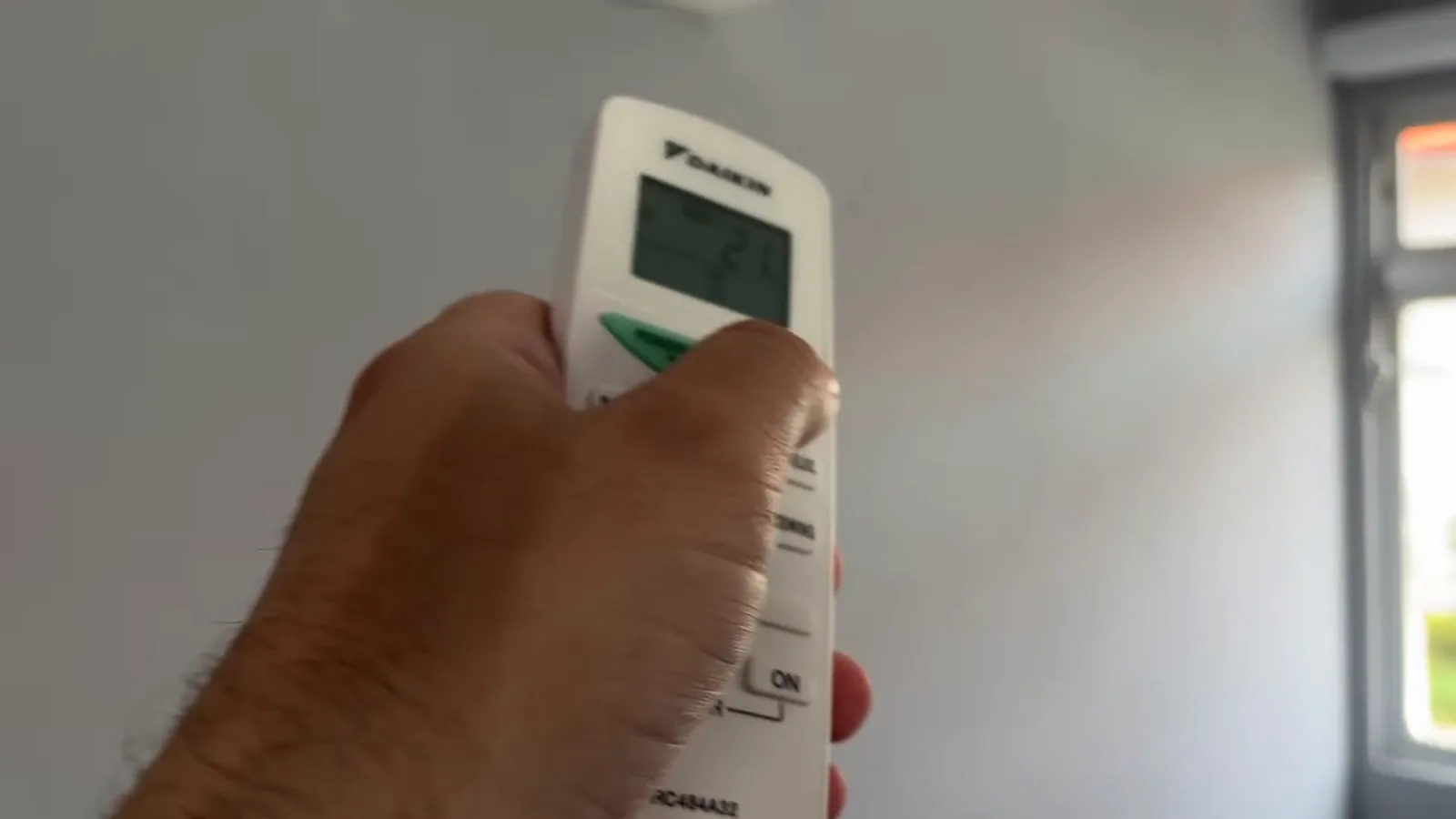 Controle remoto ajustando a temperatura do ar-condicionado Daikin no quarto