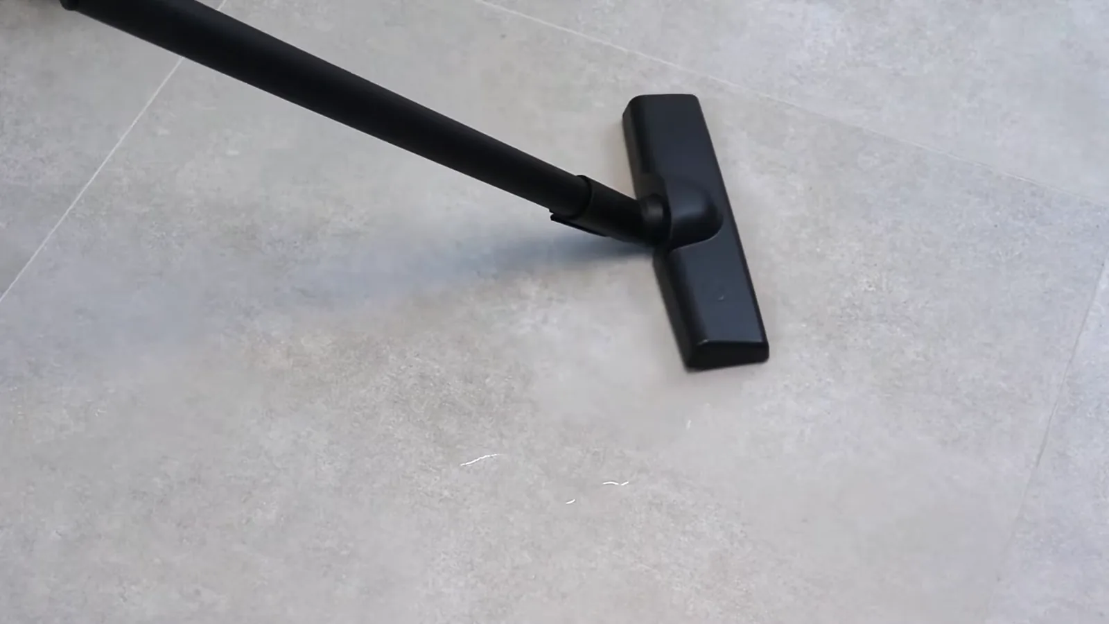 Bocal do aspirador sugando poça de água no piso