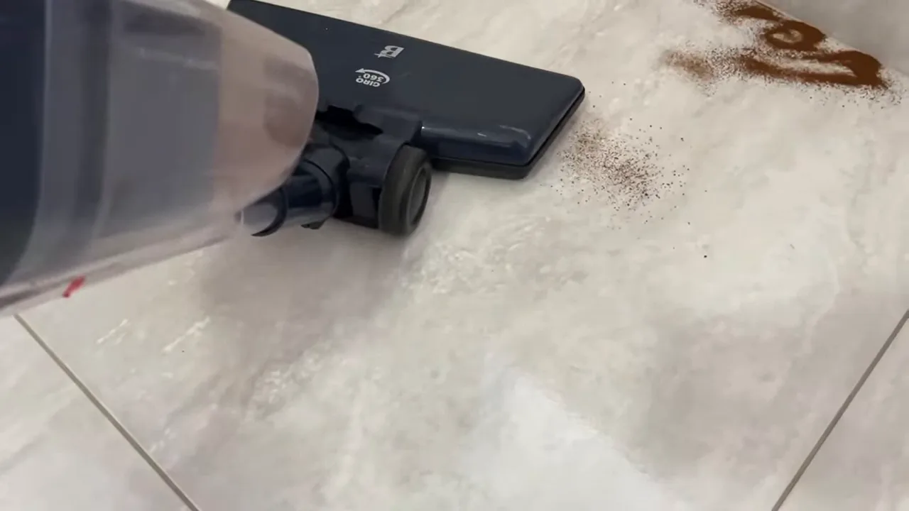 Aspirador vertical Britânia sugando sujeira em pó sobre piso cerâmico