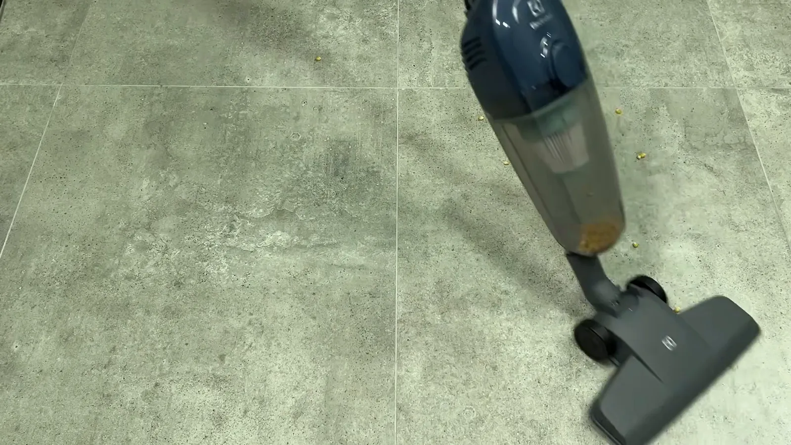 Aspirador vertical Electrolux recolhendo grãos espalhados pelo chão liso