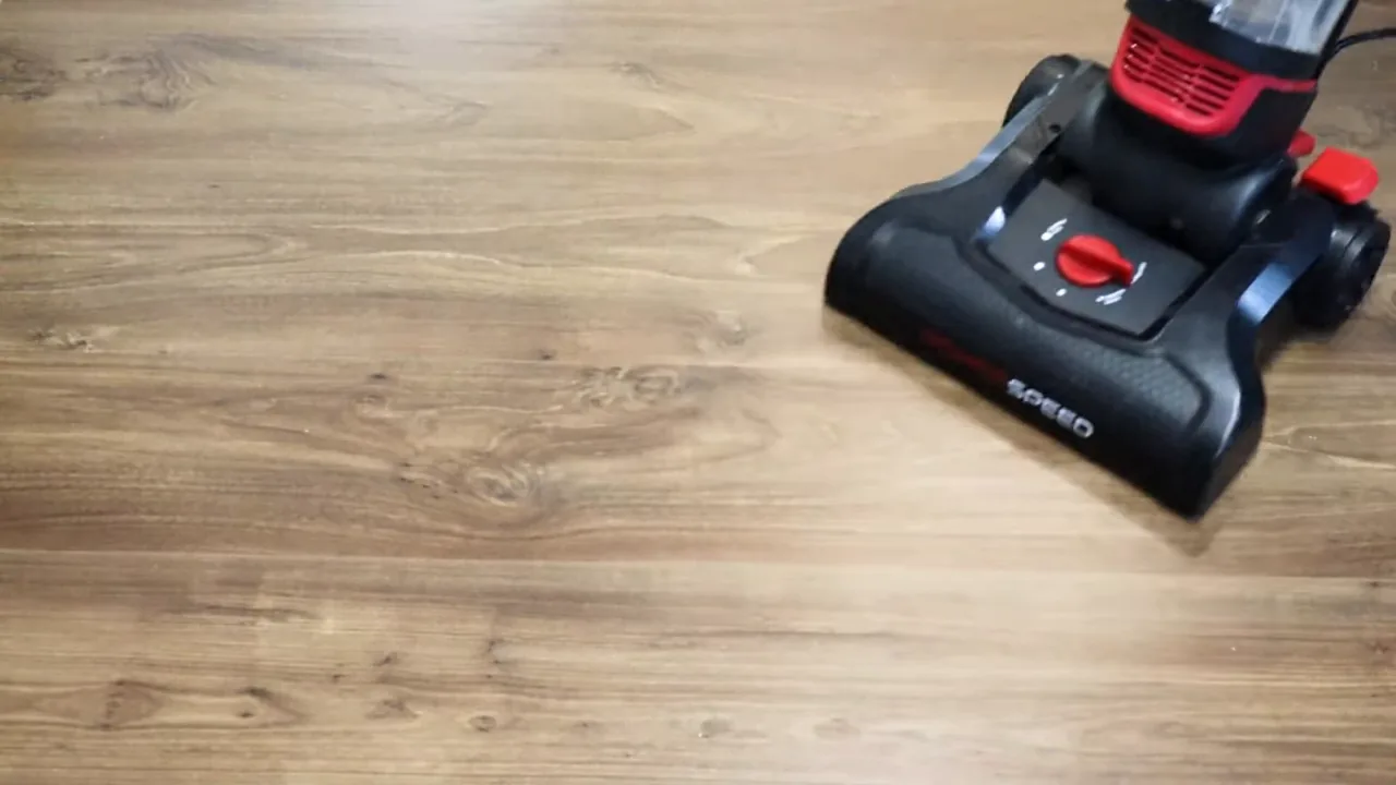 Aspirador vertical realizando limpeza contínua sobre piso de madeira laminada