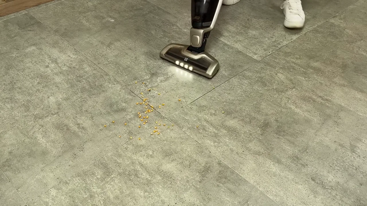 Aspirador vertical sem fio Electrolux recolhendo grãos em piso frio