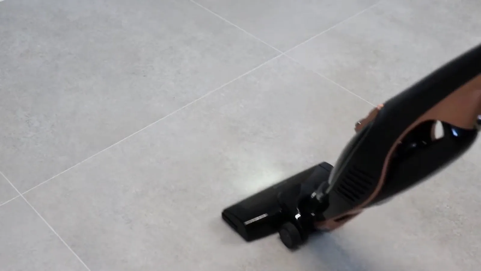 Aspirador vertical sem fio deslizando e limpando piso liso de porcelanato