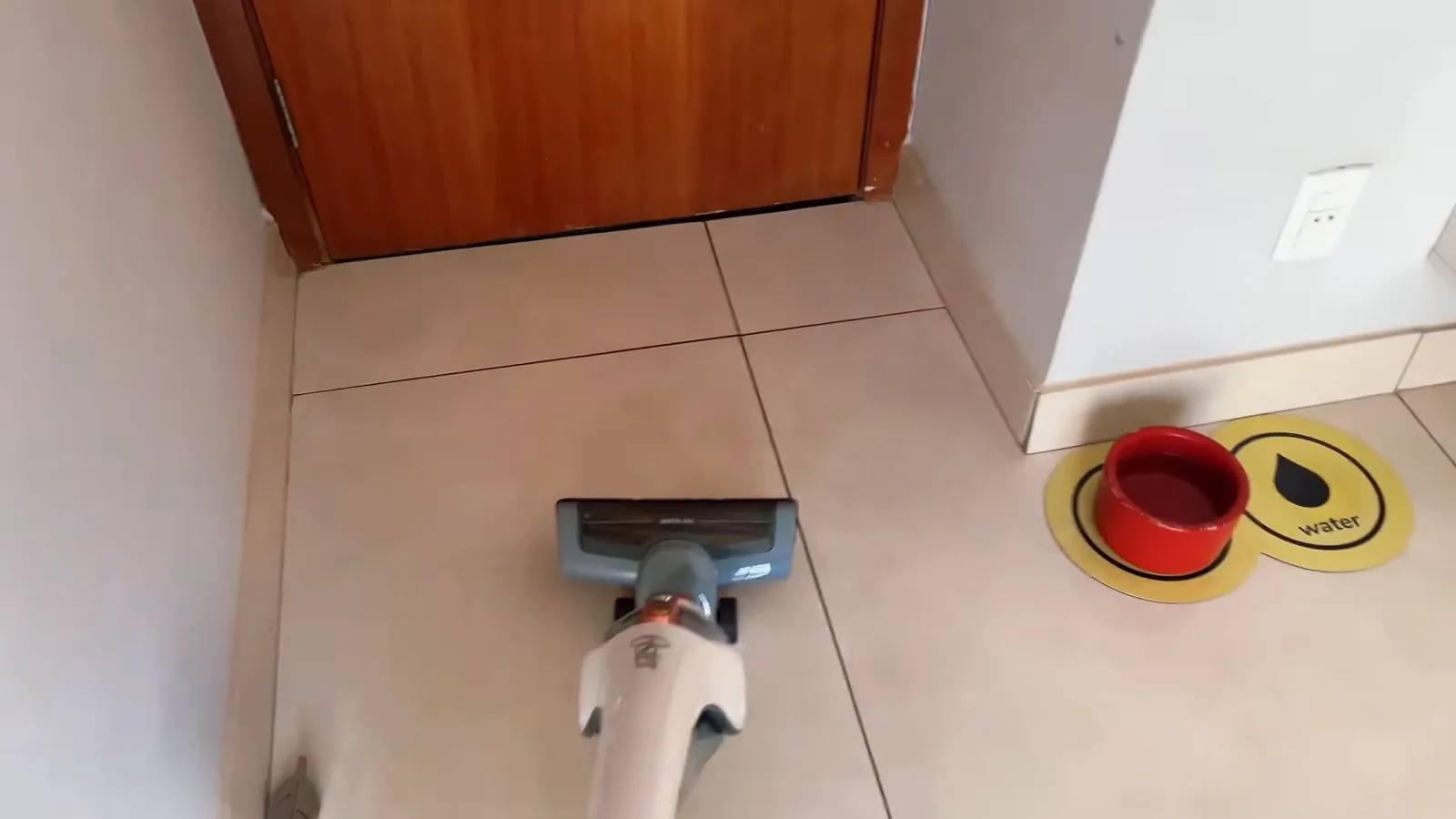 Aspirador vertical deslizando pelo piso de cerâmica durante a faxina