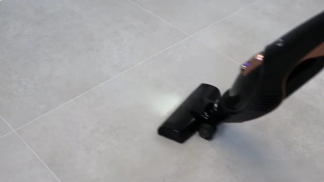 Aspirador vertical sem fio limpando piso de porcelanato em movimento contínuo