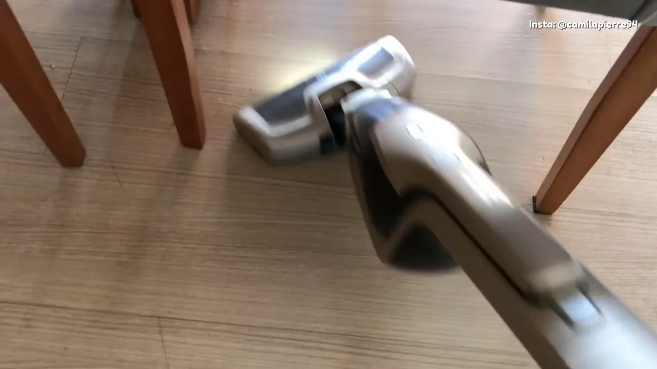 Aspirador sem fio deslizando pelo piso laminado entre móveis
