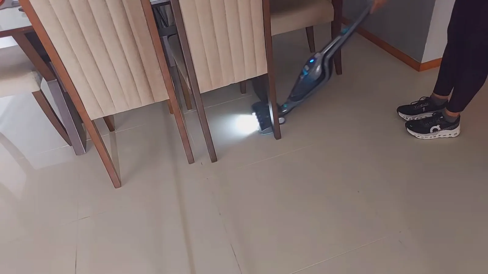 Aspirador vertical contornando pés de cadeira com luzes acesas