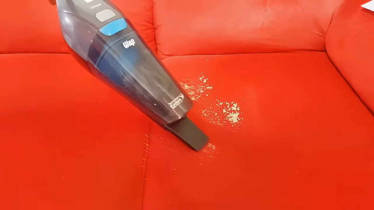 Aspirador portátil sendo utilizado para sugar sujeira do sofá