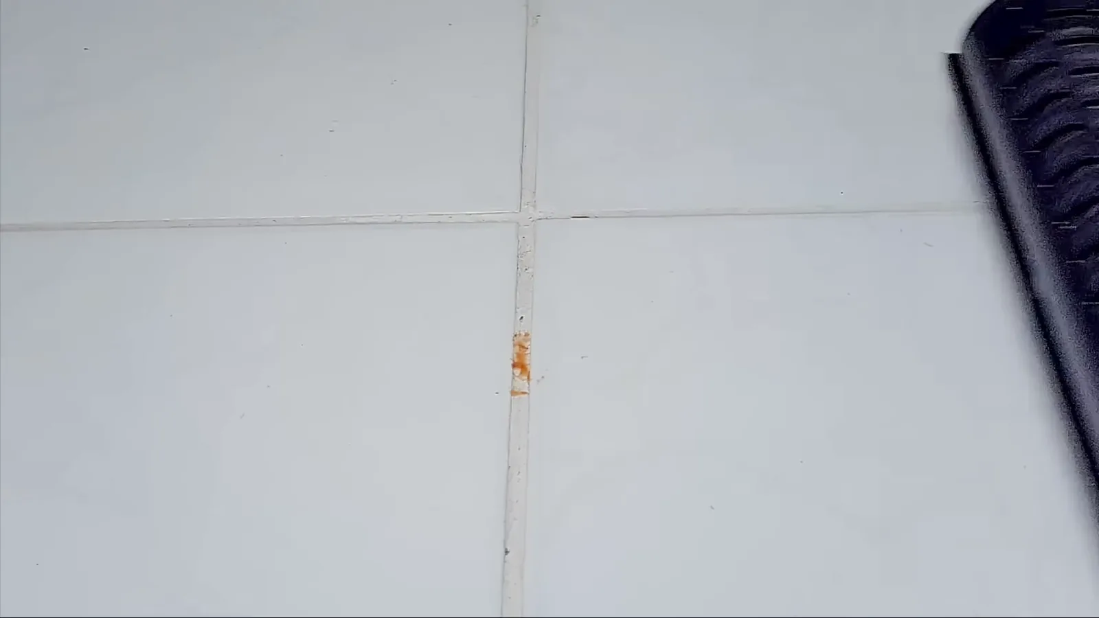 Escova rotativa do aspirador removendo manchas secas sobre o rejunte
