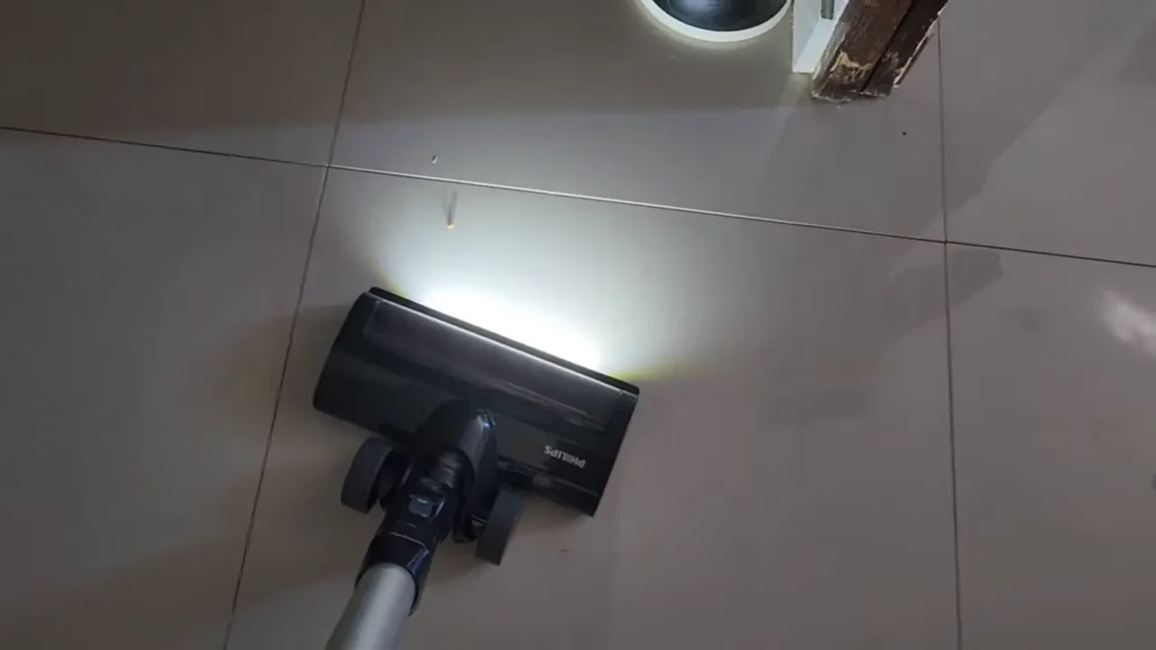 Aspirador sem fio limpando detritos no piso com iluminação LED