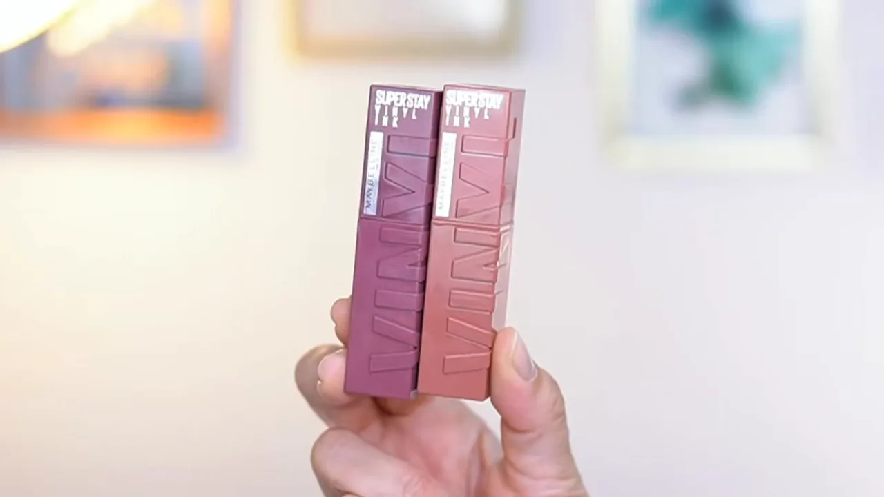 Frascos do batom líquido Maybelline SuperStay Vinyl Ink segurados na mão