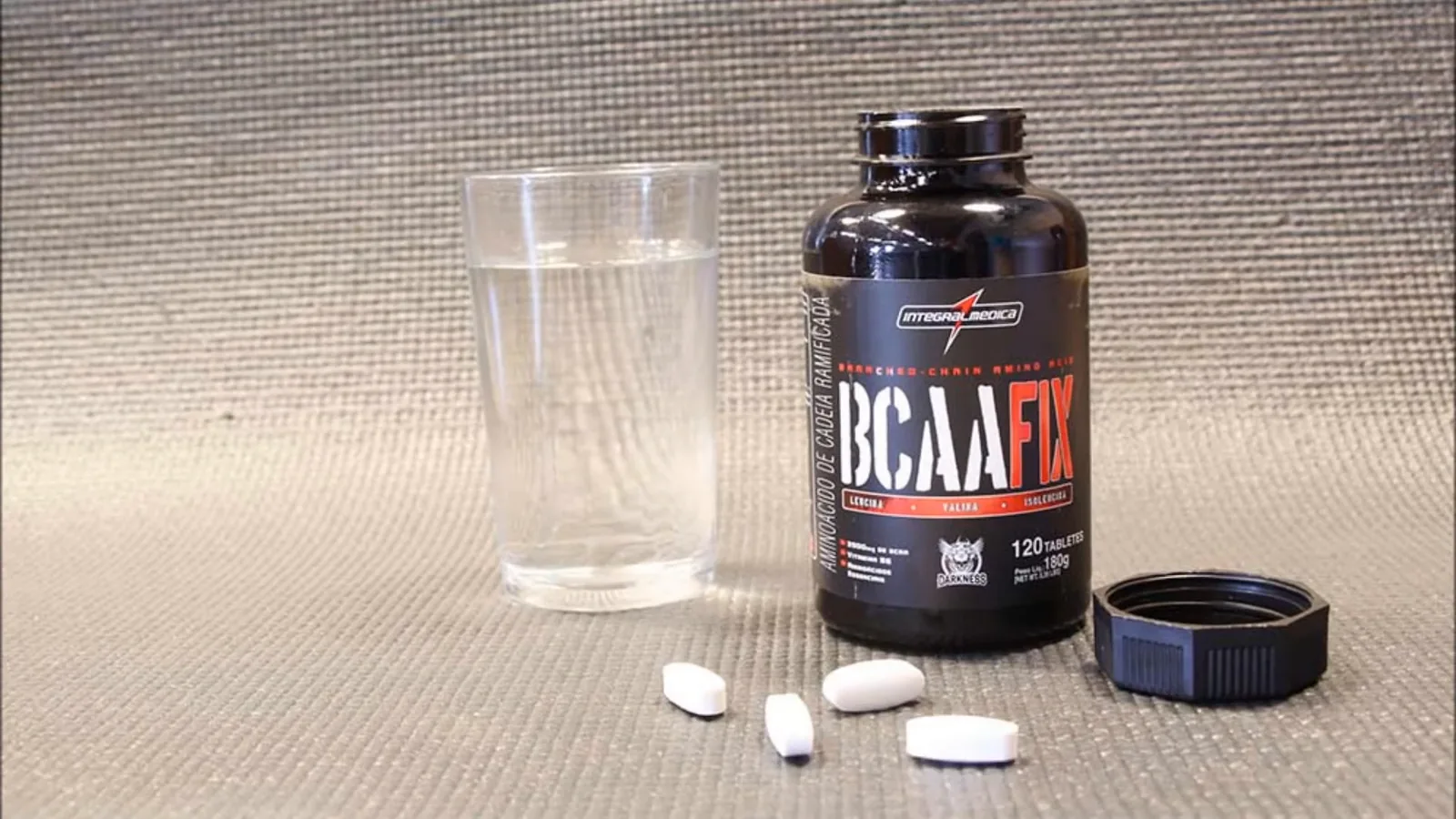 Frasco de BCAA Fix Integralmedica com três tabletes e copo de água
