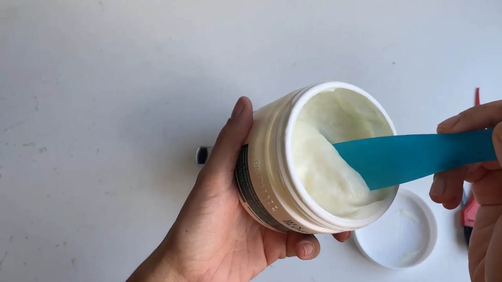 Espátula manuseando o creme reconstrutor dentro do pote Prohall