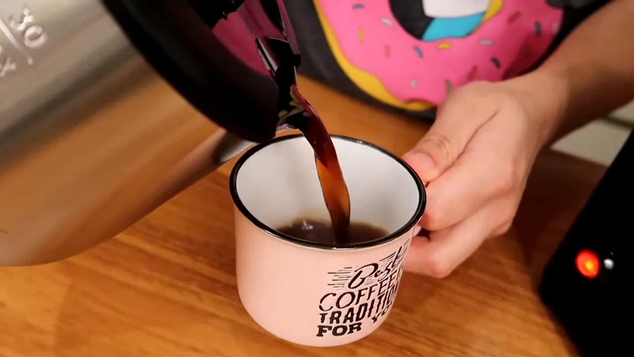 Servindo café recém-passado da jarra de inox na caneca