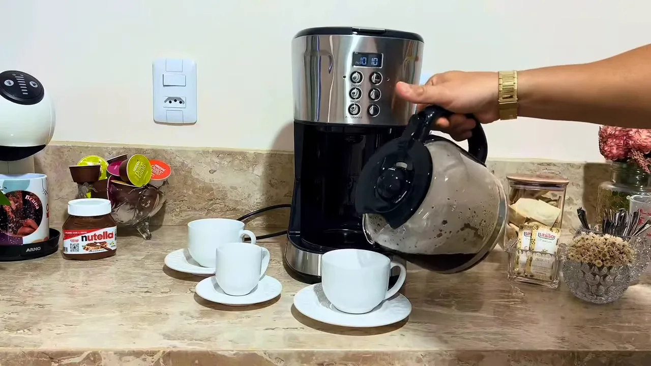 Jarra da cafeteira elétrica servindo café recém-passado na xícara