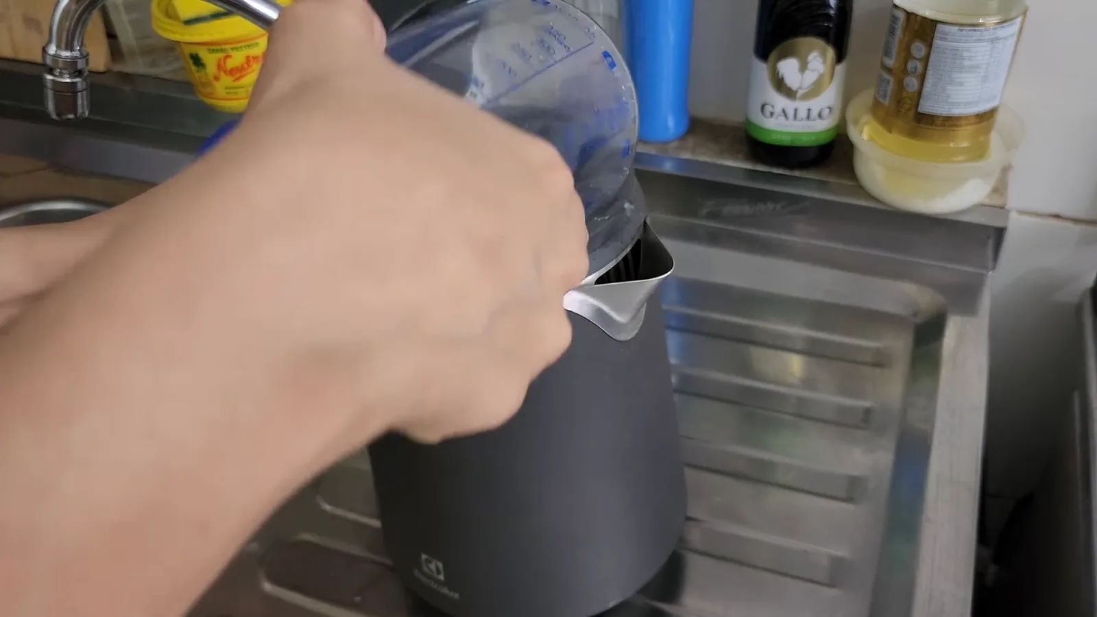 Chaleira elétrica sendo abastecida com água na pia da cozinha