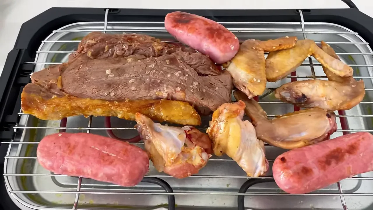 Churrasqueira elétrica assando carnes, linguiças e frango na grelha