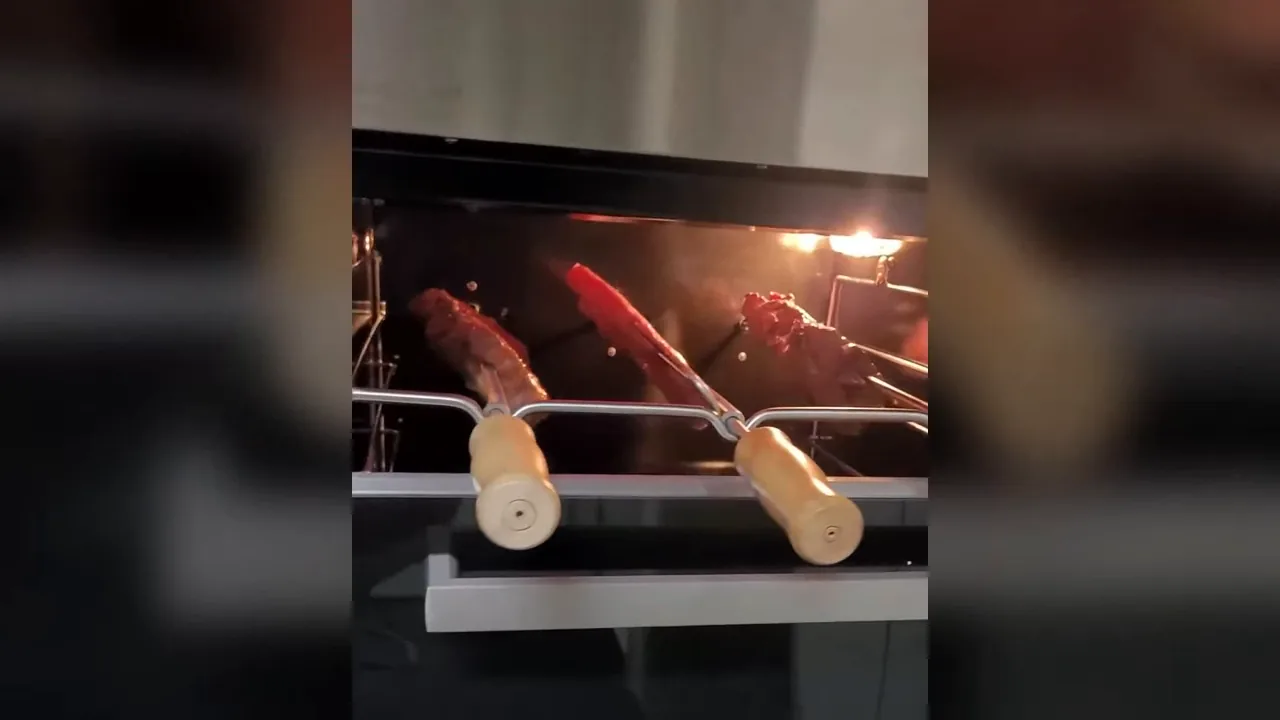 Churrasqueira elétrica embutida assando carnes e linguiças em espetos rotativos