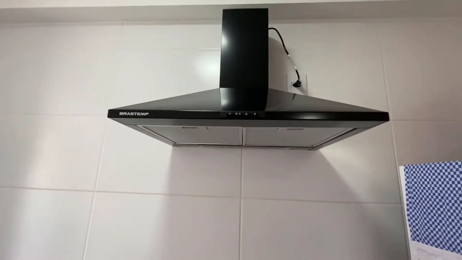 Coifa piramidal preta Brastemp fixada na parede da cozinha em uso