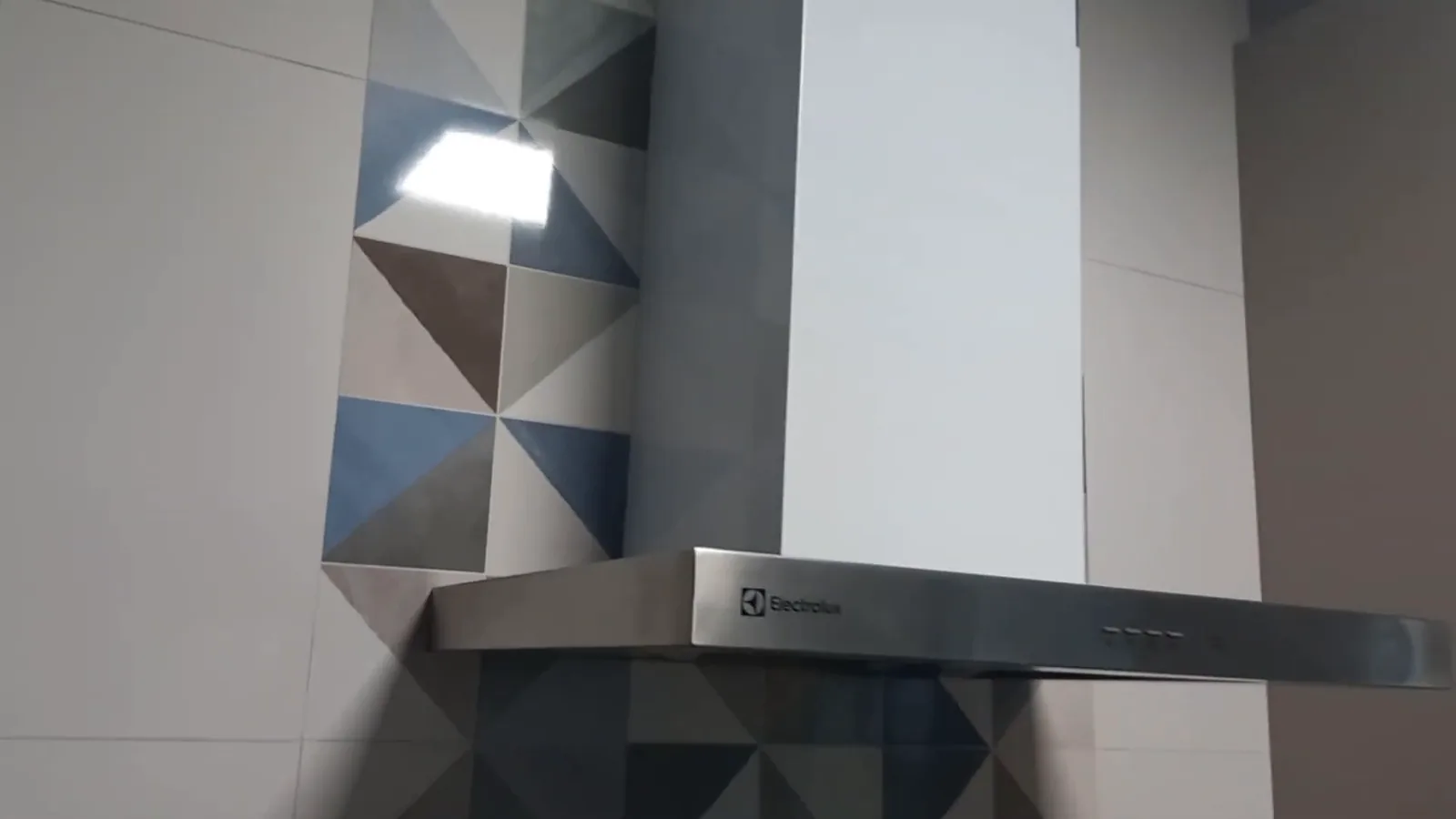 Coifa Electrolux fixada na parede acima do fogão cooktop