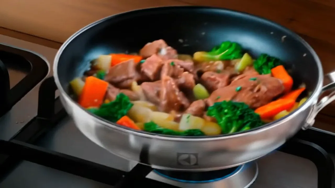 Frigideira grelhando carne e legumes no queimador potente do cooktop