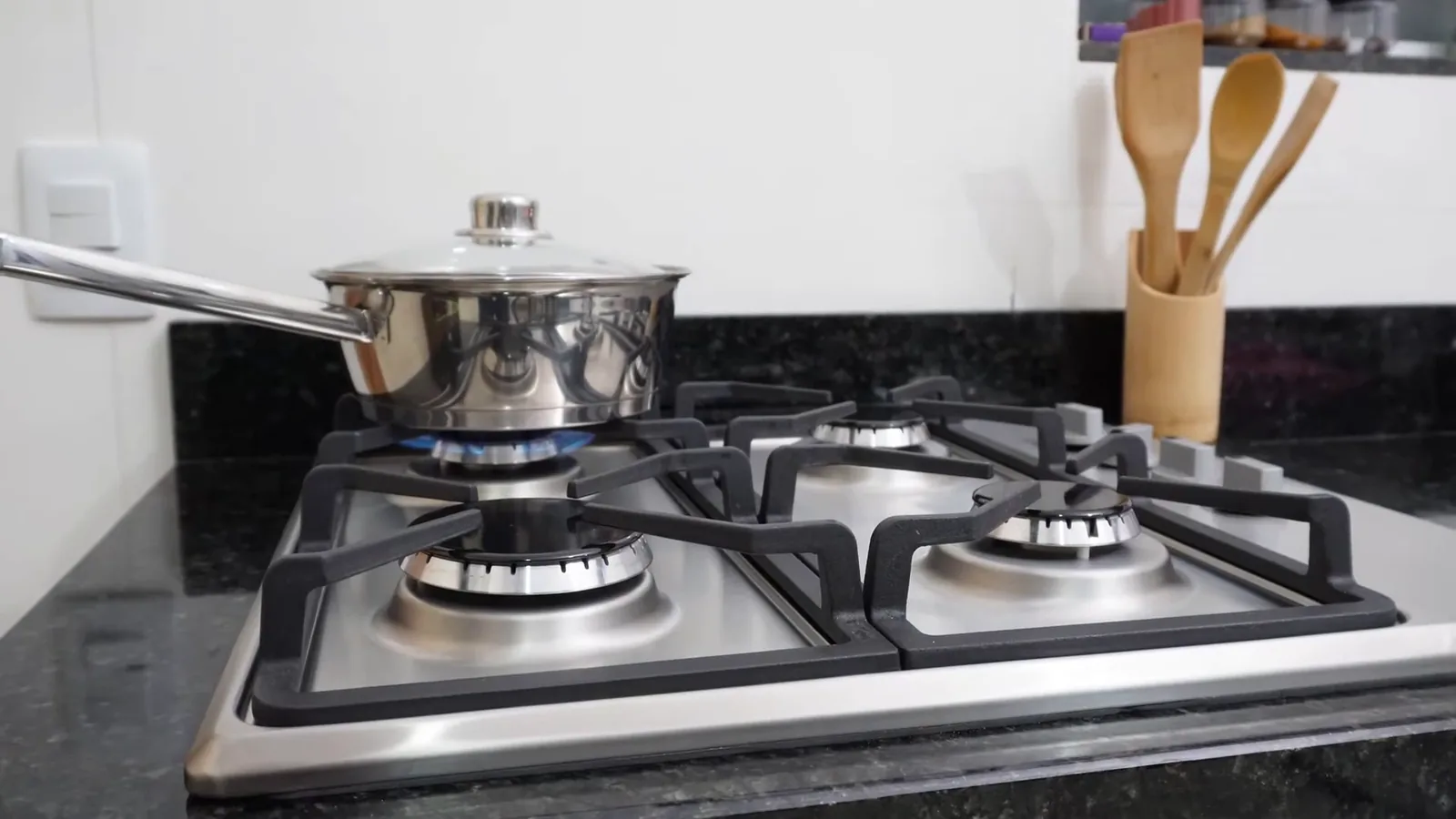 Cozimento com panela sobre queimador em funcionamento no cooktop inox