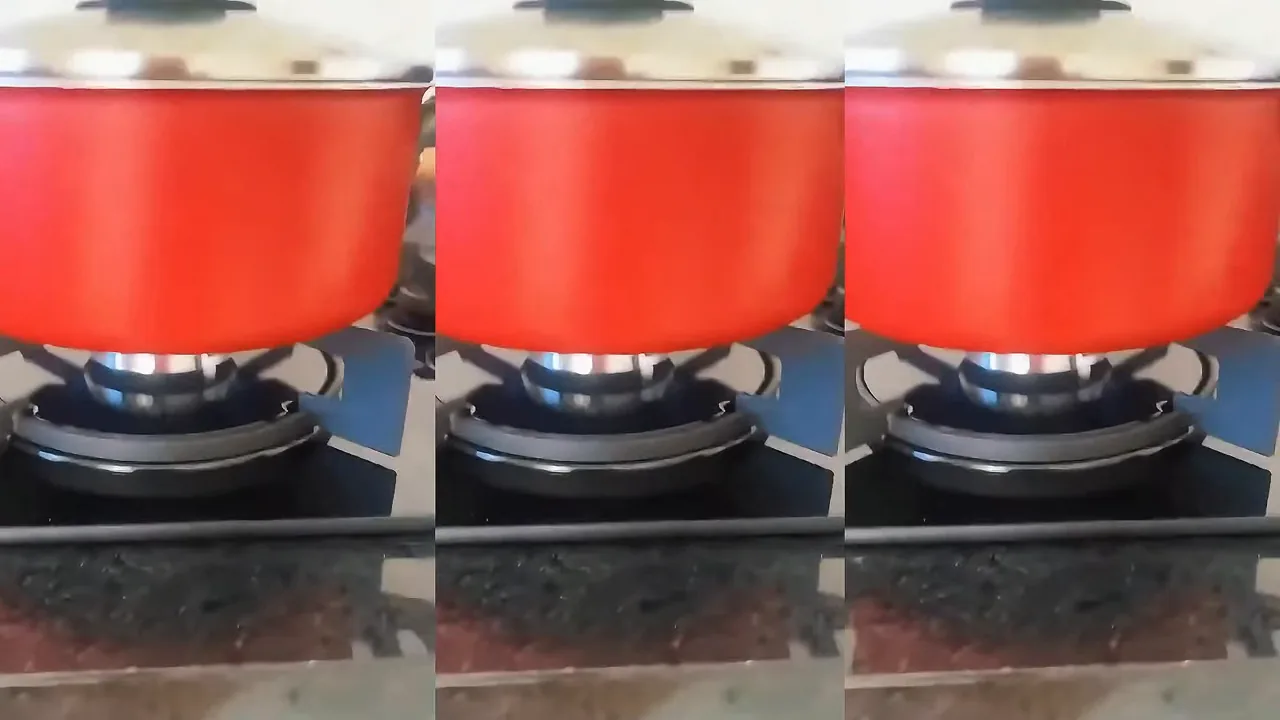 Panela vermelha no fogo com chama acesa no cooktop Electrolux