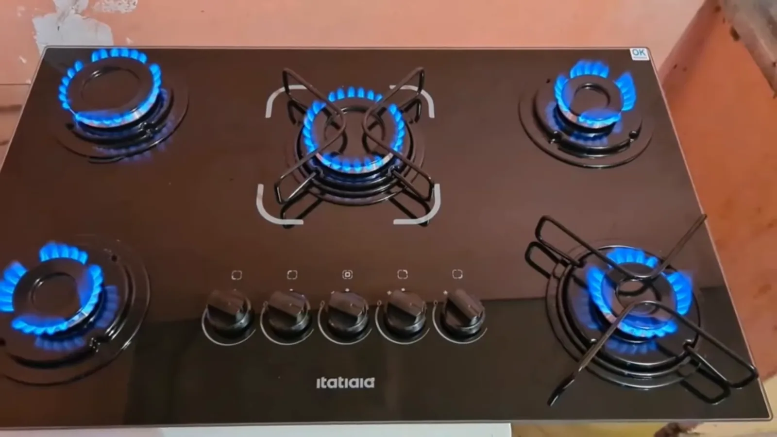 Queimadores com chamas azuis acesas no cooktop de vidro preto
