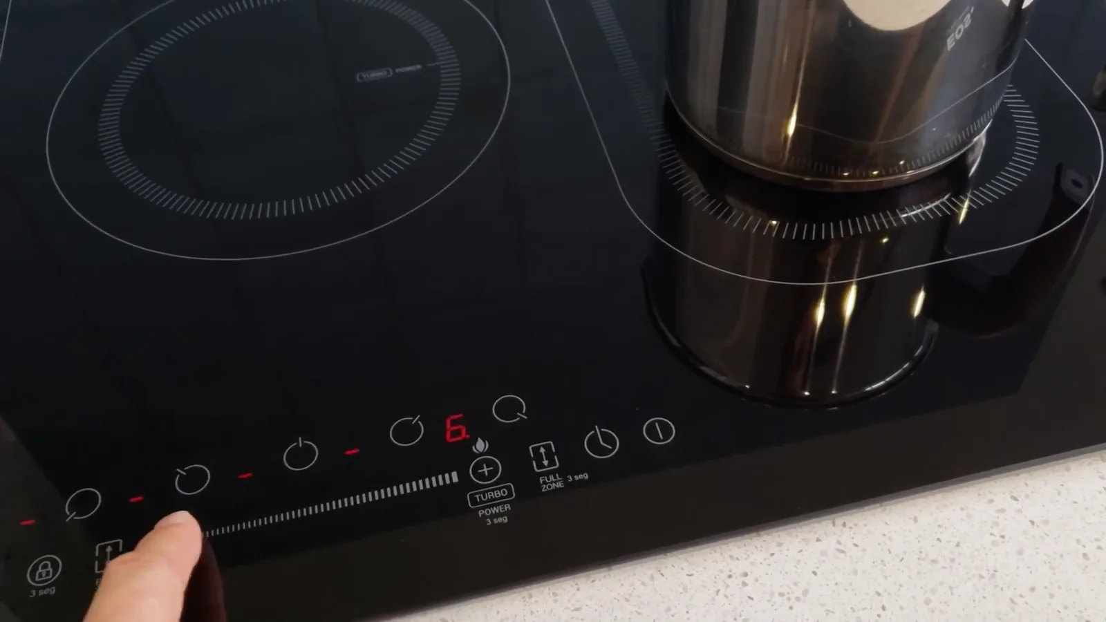 Panela de inox no cooktop durante ajuste de potência no painel
