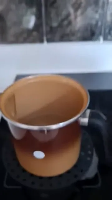 Água atingindo fervura em panela sobre o cooktop ligado