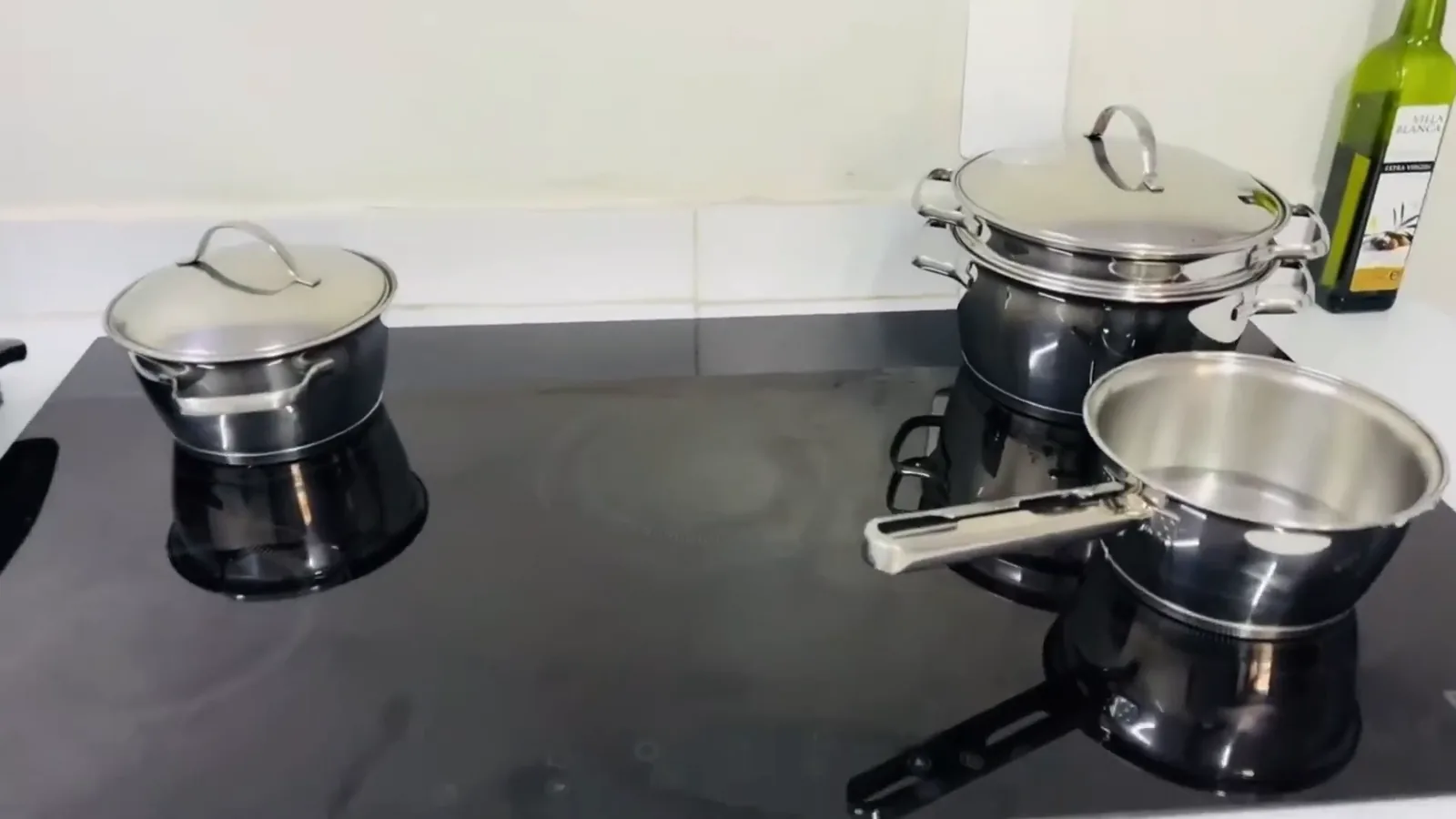 Cooktop de indução cinco bocas com panelas de inox na bancada