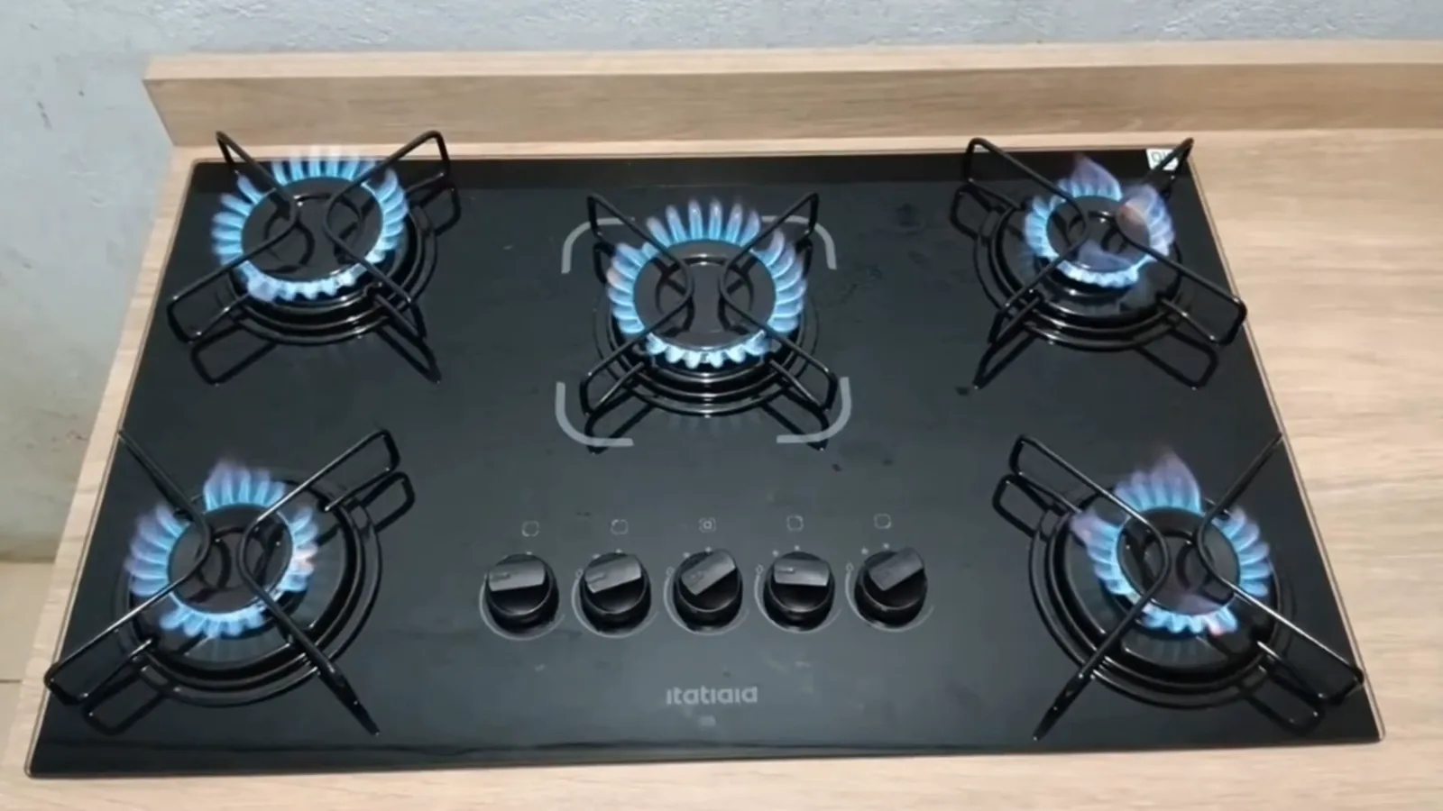 Vista superior das cinco chamas acesas no cooktop de vidro