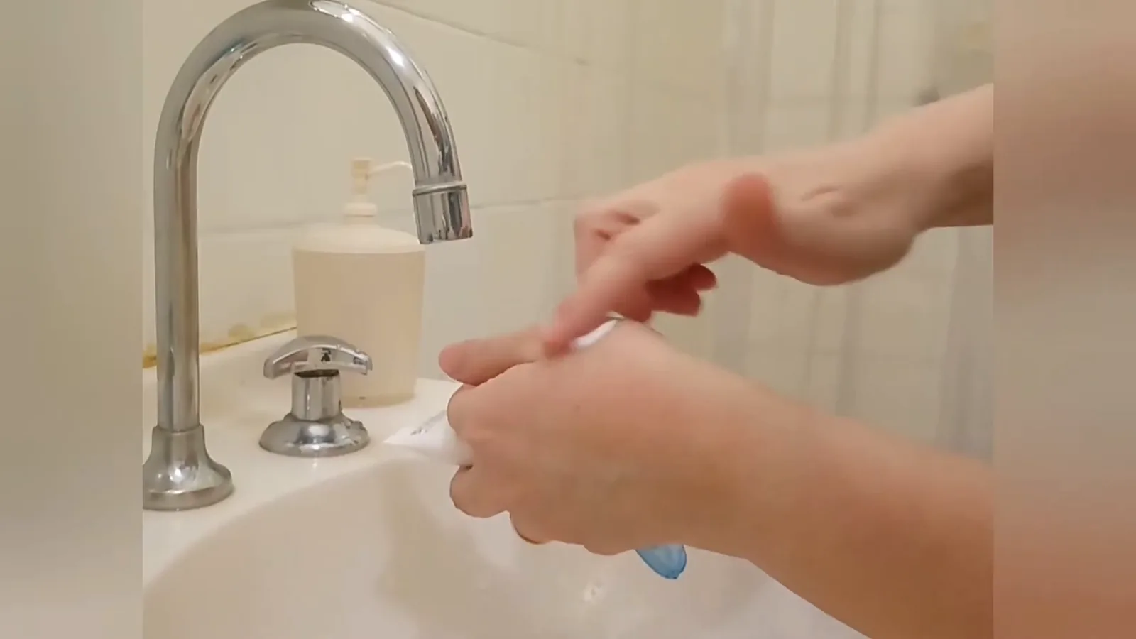 Espalhando a textura cremosa do hidratante reparador Bioderma nas mãos