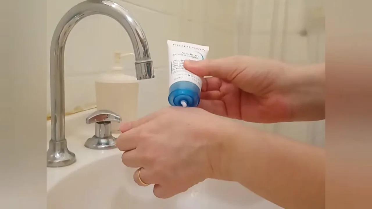 Aplicação do creme reparador Bioderma Atoderm diretamente sobre as mãos