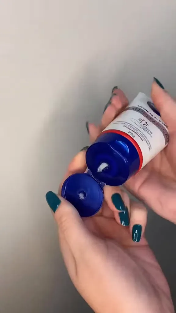 Aplicação direta do creme reparador Nivea sobre a pele da mão