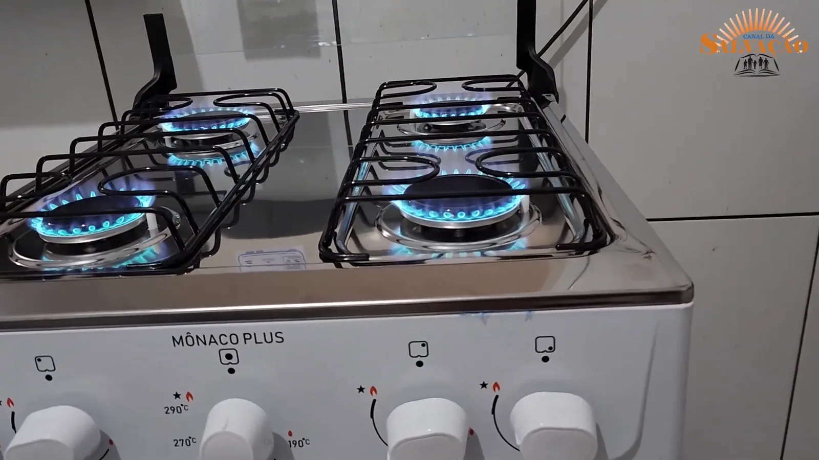 Quatro queimadores acesos em funcionamento na mesa de inox do fogão