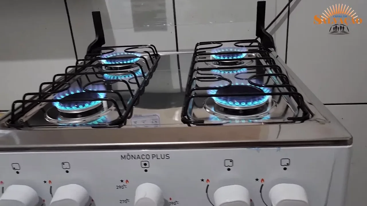 Quatro bocas com chamas acesas na mesa de inox do fogão