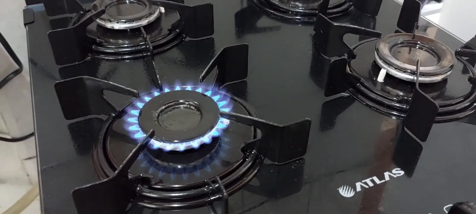 Queimador do fogão aceso com chama azul na mesa de vidro