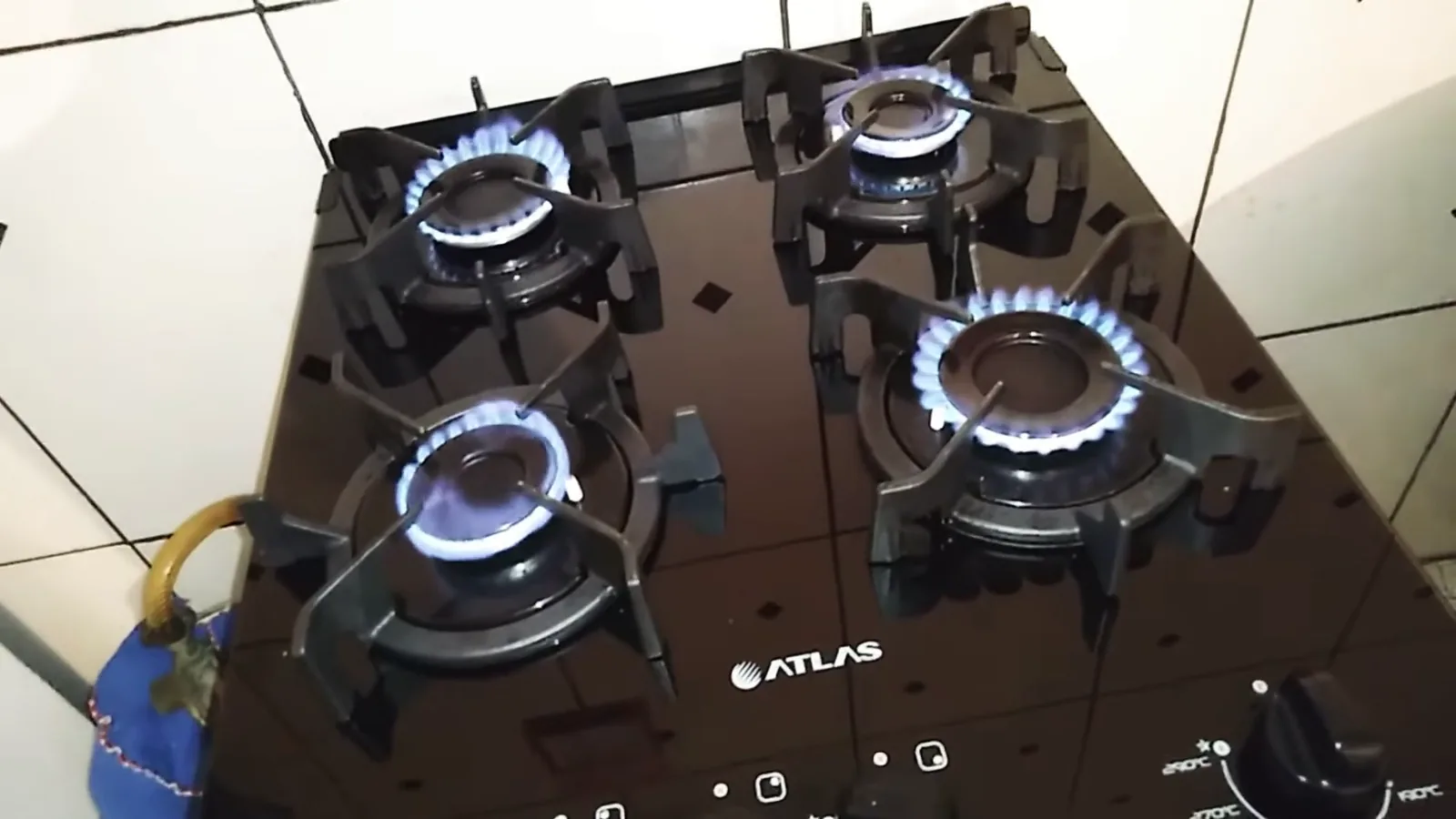 Quatro queimadores acesos sobre a mesa de vidro do fogão