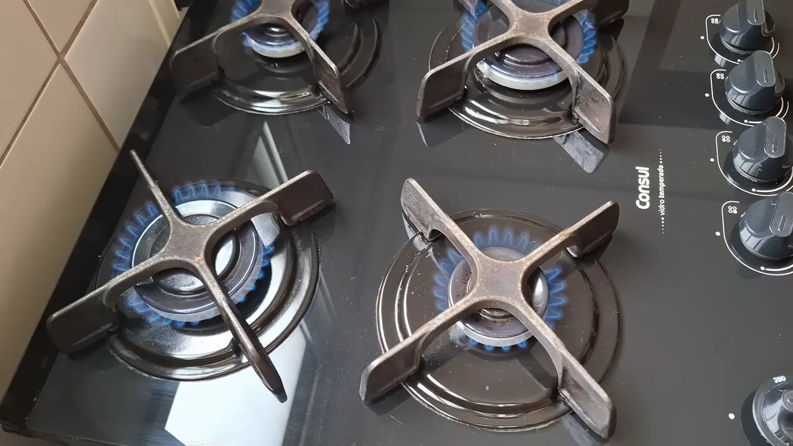 Queimadores acesos com chamas azuis na mesa de vidro temperado