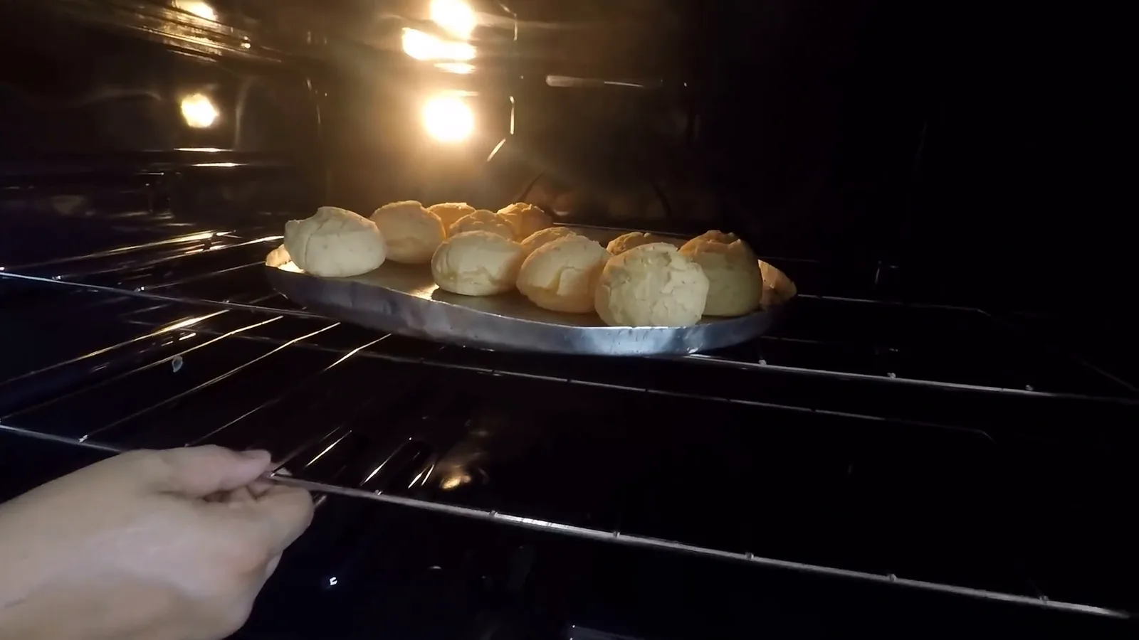 Prateleira do forno sendo puxada para frente com assadeira