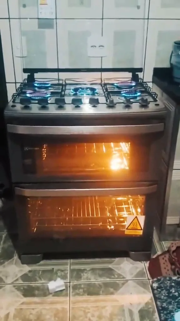 Fogão Electrolux com cinco chamas acesas e fornos iluminados