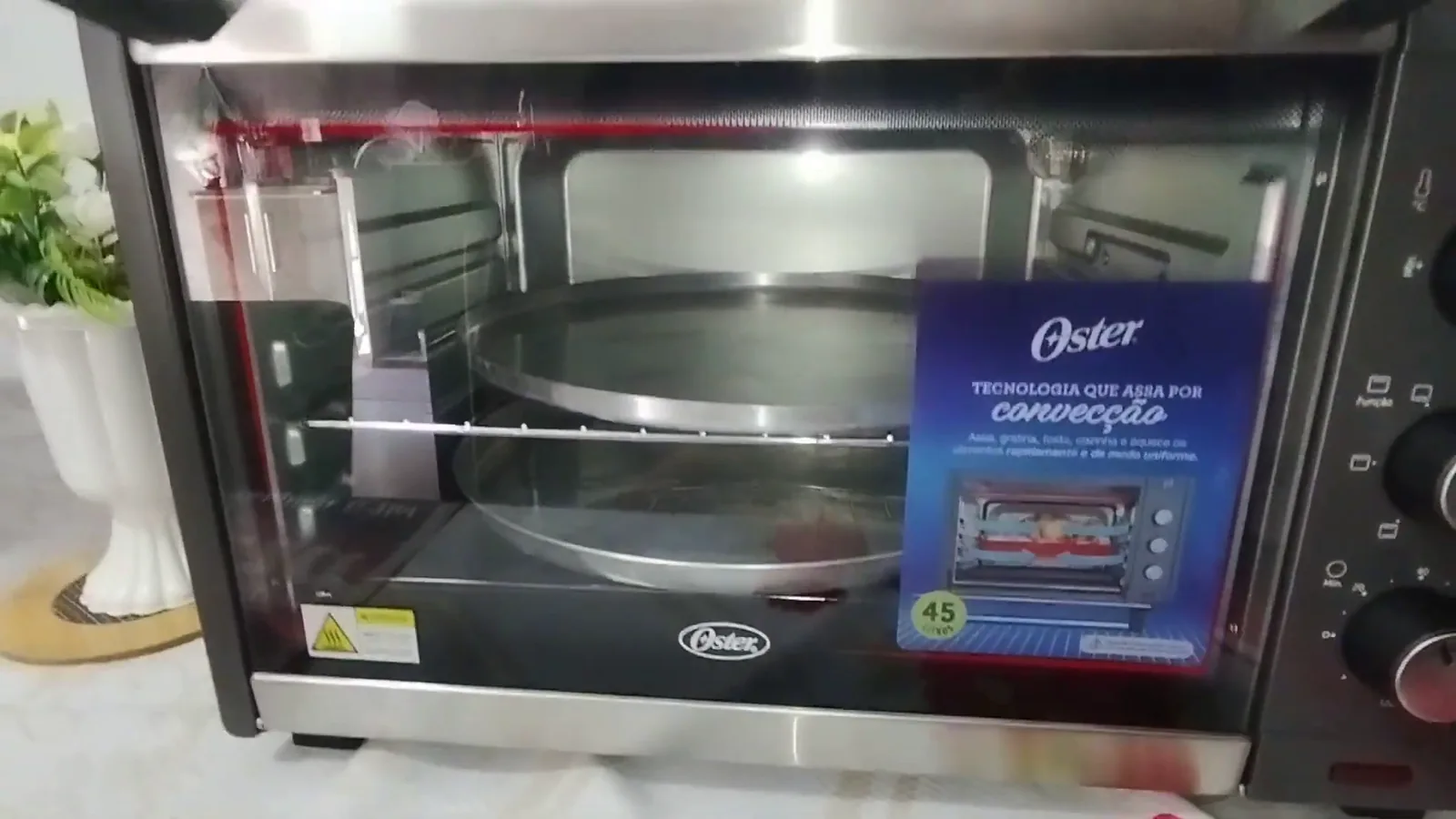 Forno elétrico Oster fechado com duas formas de pizza no interior